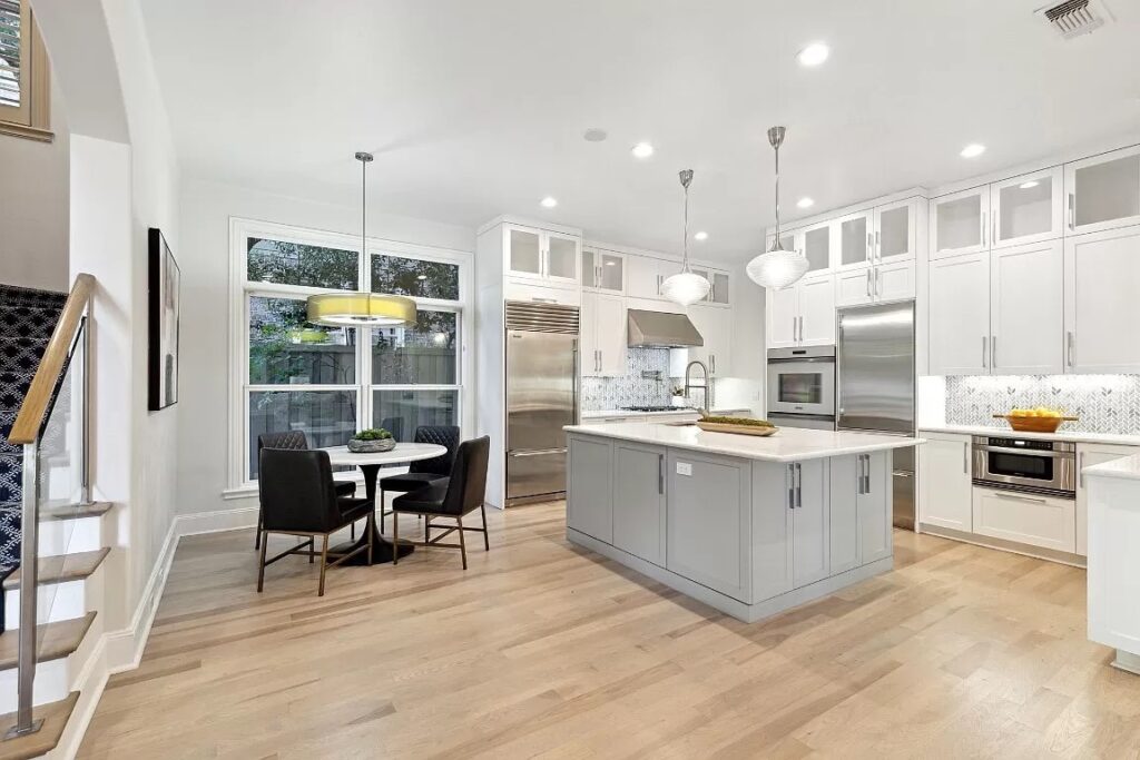 Staged kitchen with small round dining table and four leather chairs
