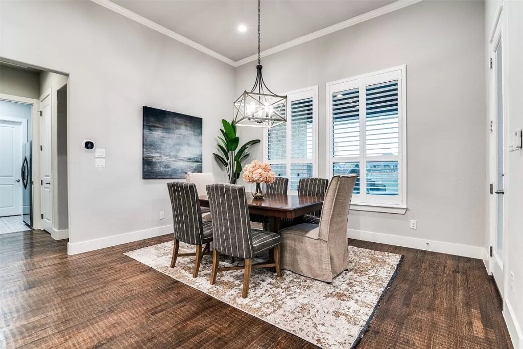 Dining room in home stage with wooden rectangular table and 6 upholstered chairs