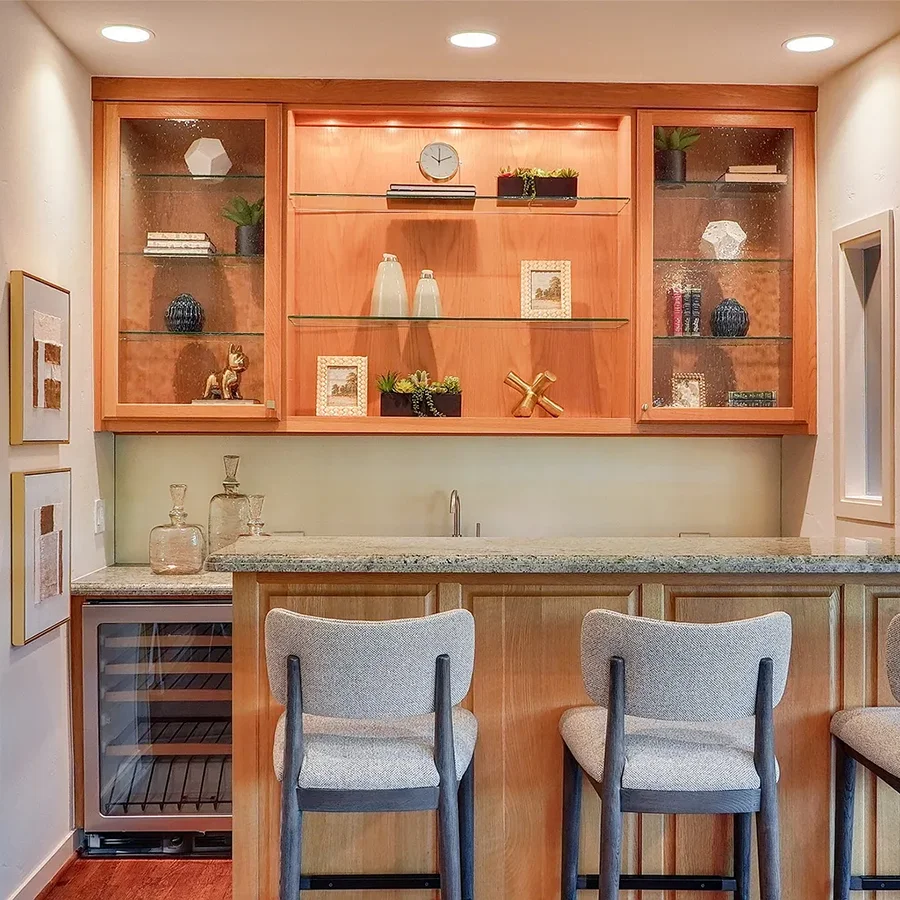Bar area staged with grey barstools, glassware, greenery and small mixed media artwork