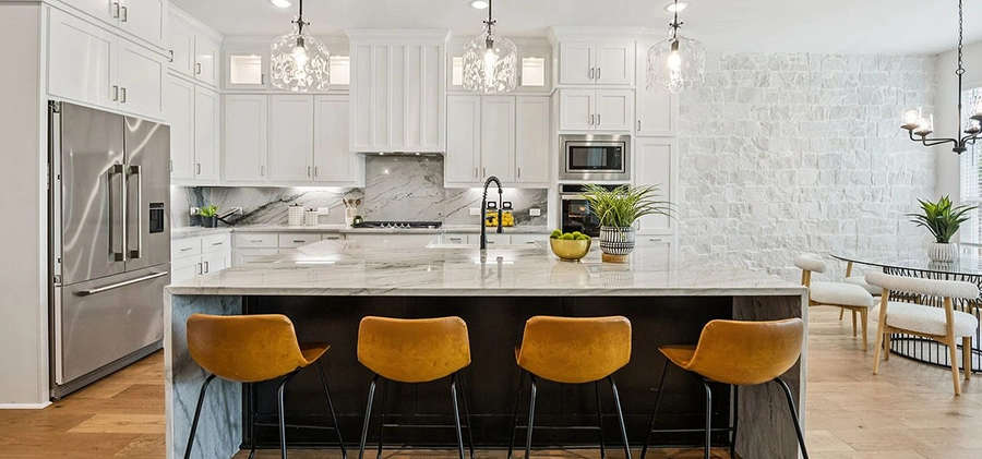 Kitchen and dining area staged with four low back leather barstools, round table with four white chairs and kitchen accessories