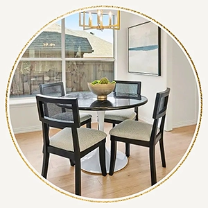 Staged dining room table with four black chairs, round table with a white base and large abstract artwork