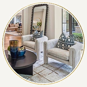 Seating area with two grey chairs, geometric fabric pillows, black round coffee table and a large standing mirror