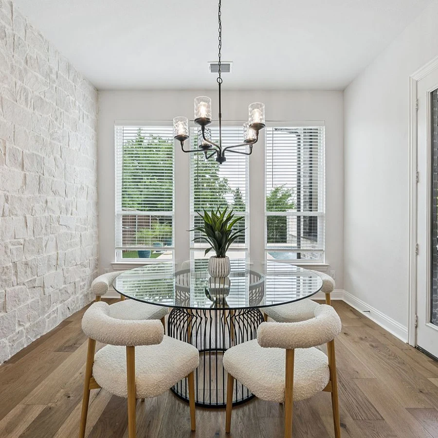 Small dining area staged with a round glass table and four white boucle chairs