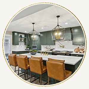 Circular vignette of a staged kitchen highlighting sage green cabinets, quartz countertops, a black range, and four tan leather barstools