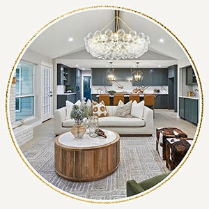 Circular vignette of a staged living room showcasing a round wood coffee table, a white sofa, cowhide footstools, and a large bubble-glass chandelier
