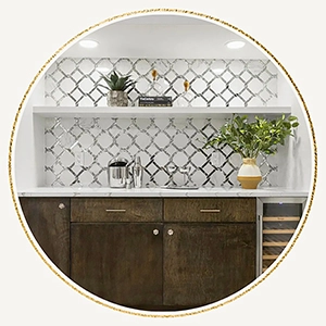 Circular vignette of a staged home bar showcasing dark wood lower cabinets, a wine refrigerator, white quartz countertops, and a reflective silver geometric tile backsplash