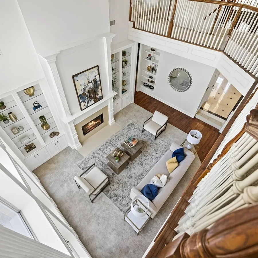 View of a large staged living room from the upstairs balcony looking down
