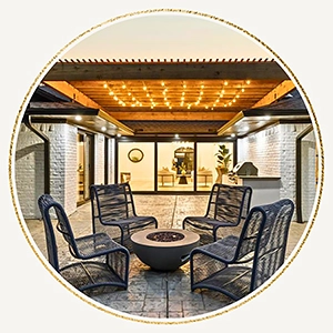 Outdoor seating area staged with four black modern mesh chairs and a small round firepit