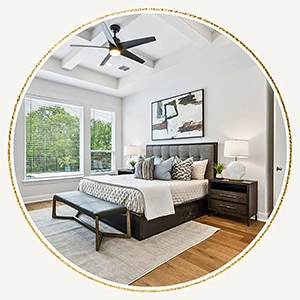 Staged bedroom with a grey upholstered headboard and wood frame, black bench and two wooden nightstands