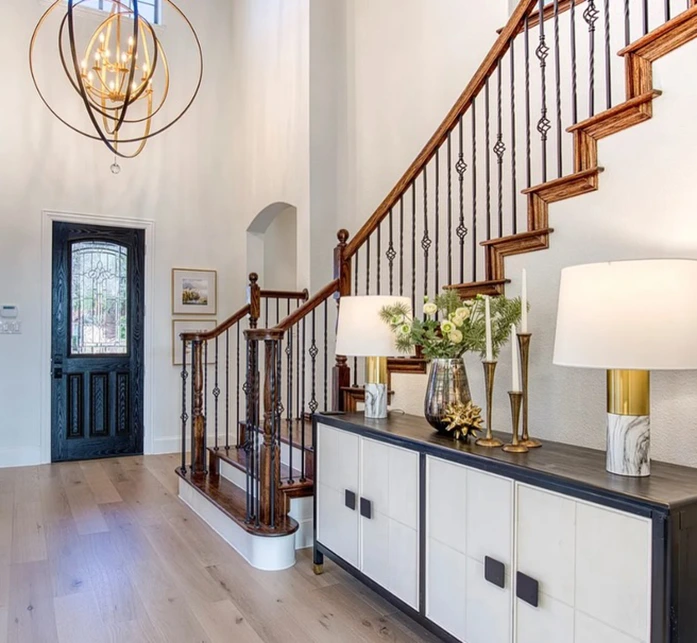 Large entryway staged with several small art pieces, a black and white console table, and two gold and white lamps