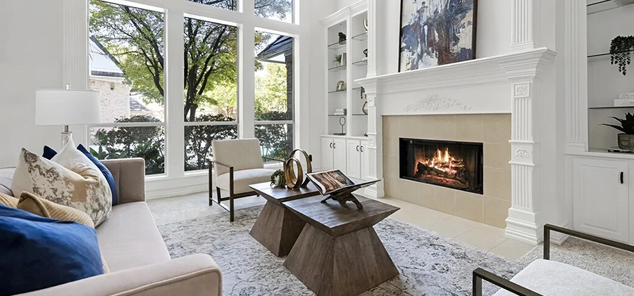 Living room with grey sofa, blue and camel colored pillows, two square coffee tables and a white side chair