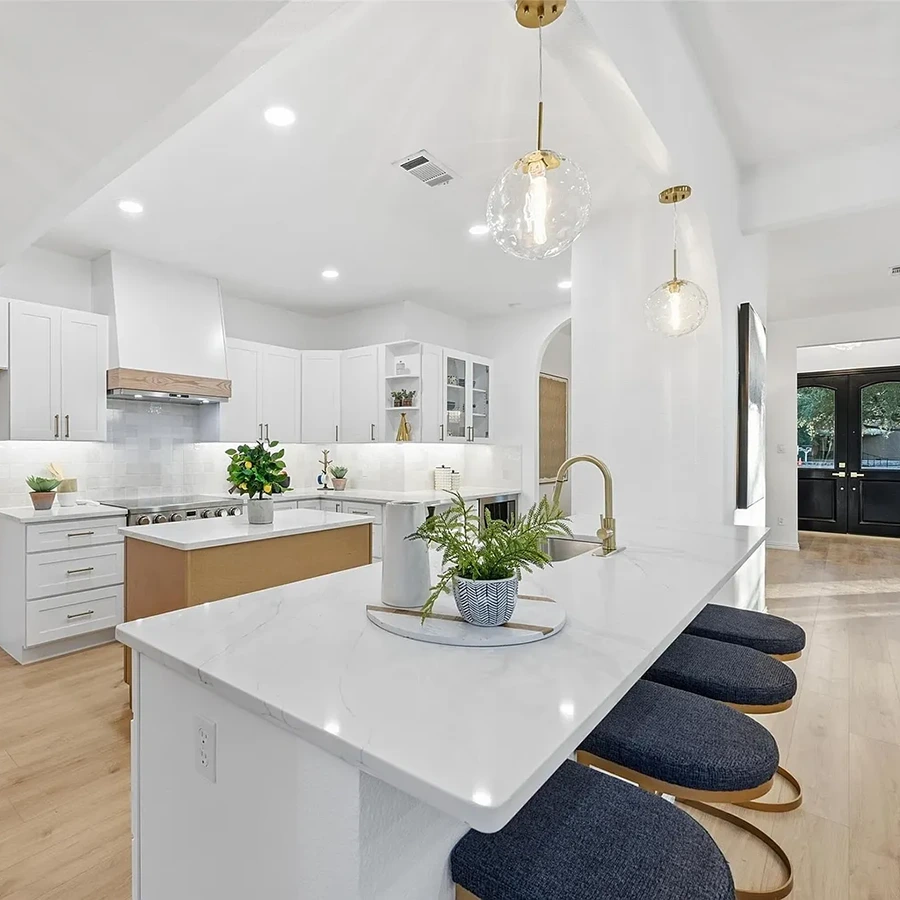 Modern kitchen with white countertops and cabinets, black barstools with metal legs and kitchen accessories