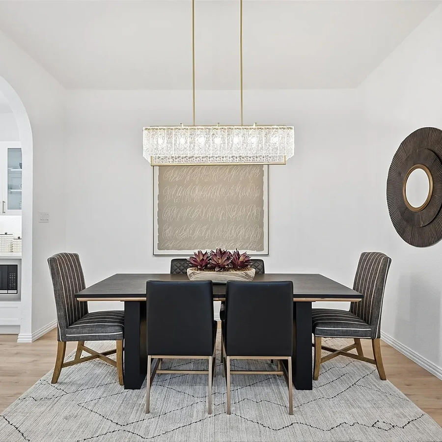 Dining room with a large wood rectangular table, six brown chairs, and a large rectangular glass chandelier.