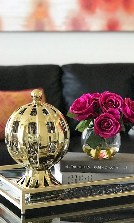 Coffee table staged with gold accessories and faux flowers