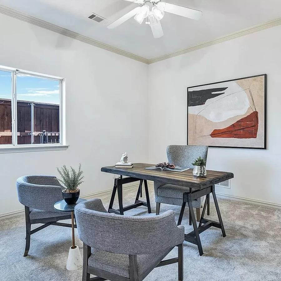 Staged home office with wooden desk, grey chairs and abstract artwork