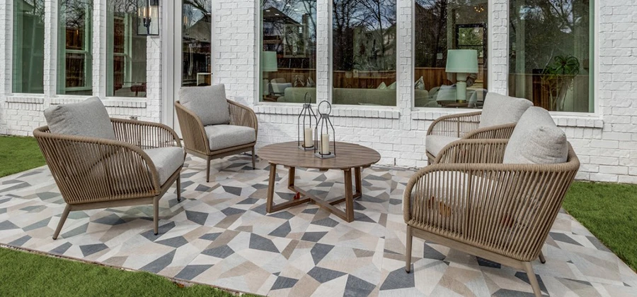 Outdoor area staged with four chairs with grey cushions and a round matching coffee table