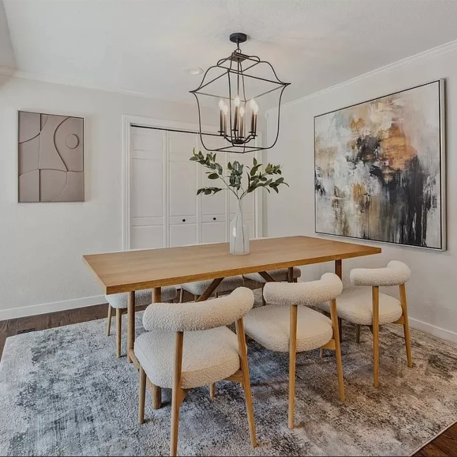 Dining area featuring a light wood rectangular table, four boucle chairs and light abstract artwork