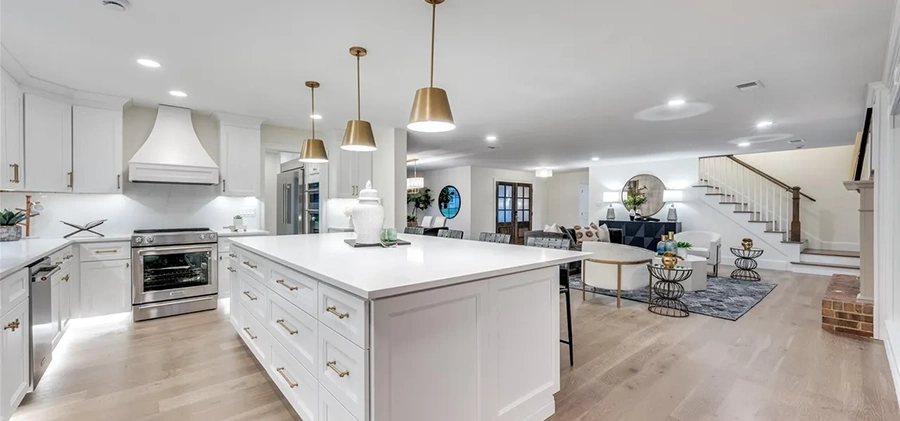 Bright open-concept kitchen view highlighting a large white island with gold hardware and a seamless transition to the living area