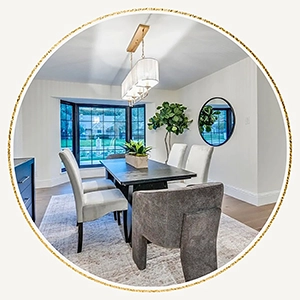 Circular vignette of a staged dining room featuring a dark rectangular table, grey and white chairs, and a large fiddle-leaf fig tree
