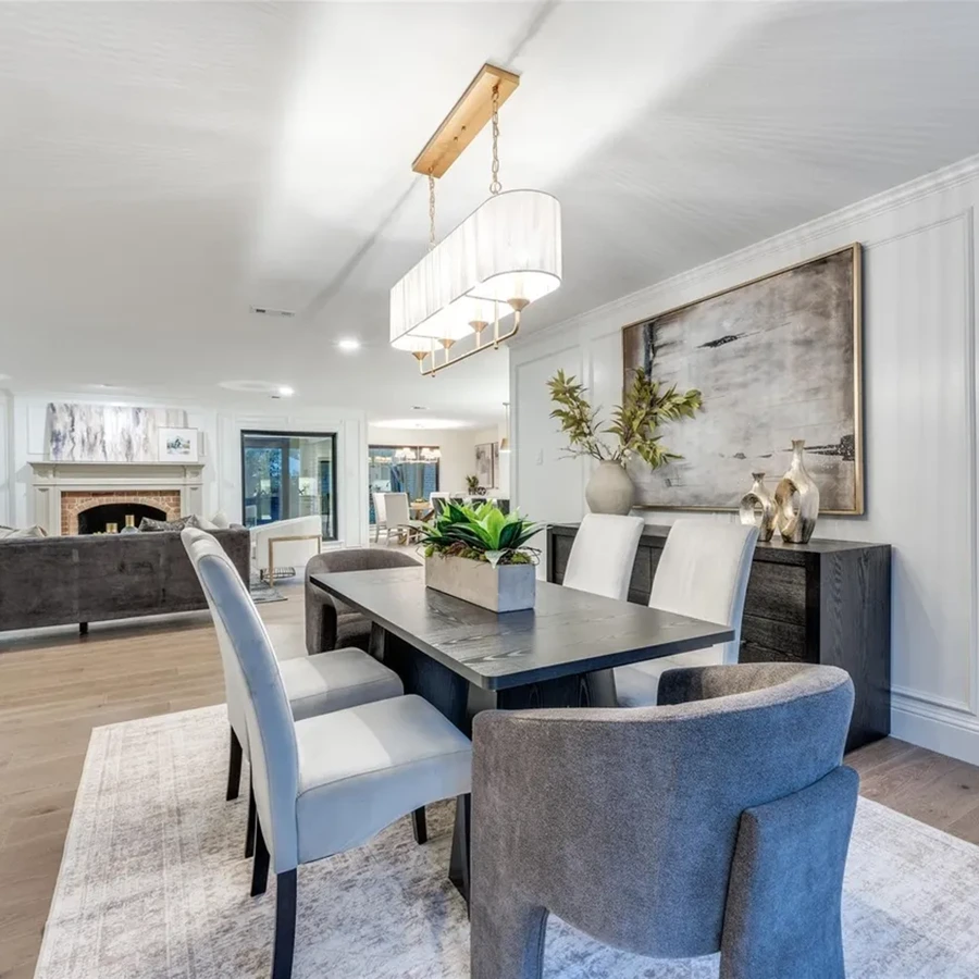 Formal dining room staging highlighting a dark wood table, mixed grey and white chairs, and a linear shaded chandelier