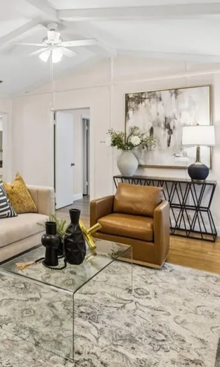 Living room vignette with a cognac leather armchair, glass coffee table, and an geometric console table beneath abstract art