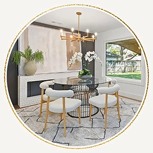 Round dining room vignette featuring a glass-top table, four modern cream chairs, an orchid arrangement, and a gold chandelier