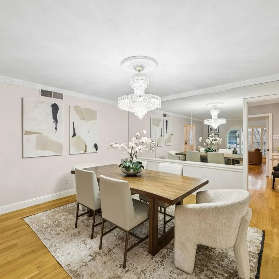 Formal dining room with a mid-century wooden table, cream chairs, and a crystal chandelier