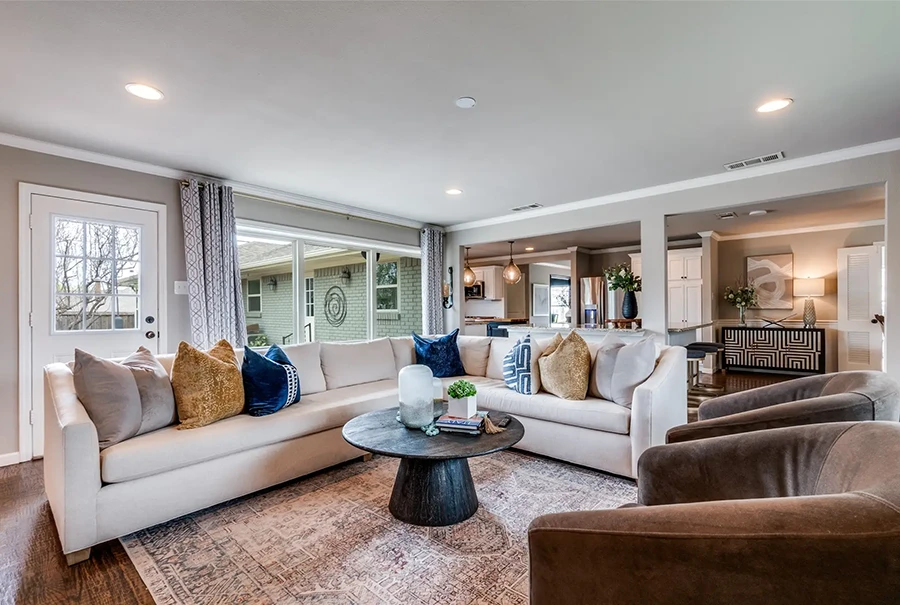 Spacious staged living room with a large white sectional, velvet accent pillows, and dark brown armchairs