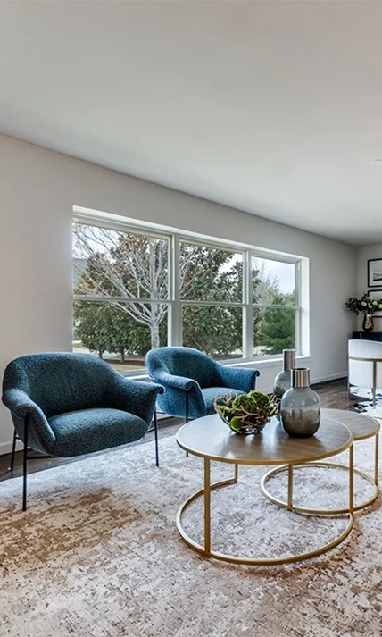 Close-up of two textured teal armchairs next to a nesting gold coffee table set on a patterned rug