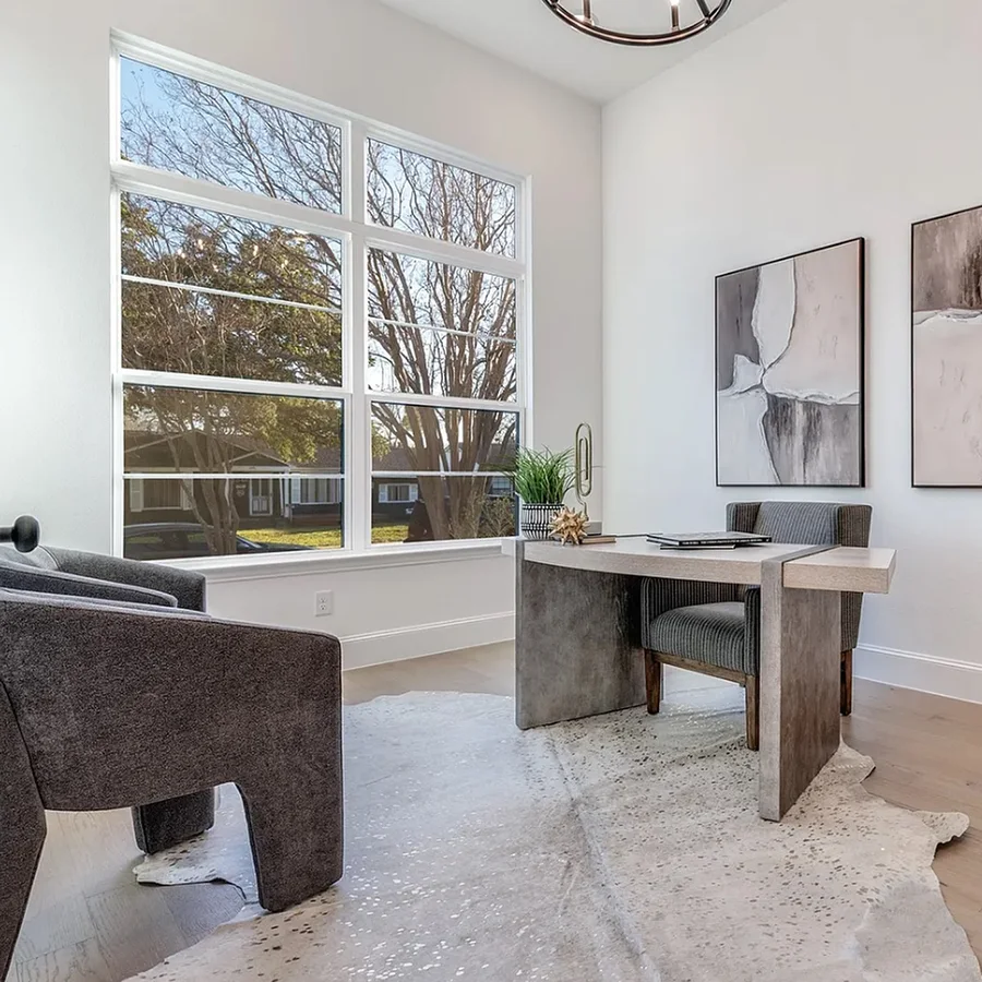 Staged office with modern grey desk, grey desk chair, two grey guest chairs and a rawhide rug