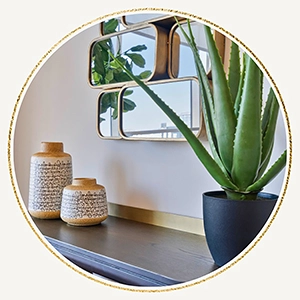 Close up of accessories on a black console table including two small vases and an abstract mirror
