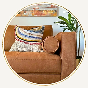Closeup of a tan sofa staged with a multicolored pillow and matching artwork