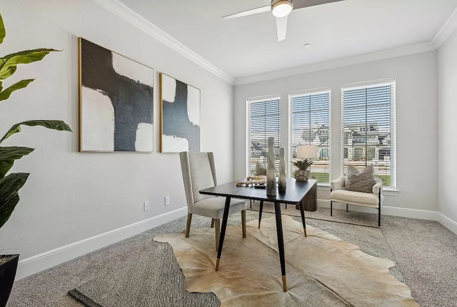 Staged home office with modern desk, two guest chairs and rawhide rug