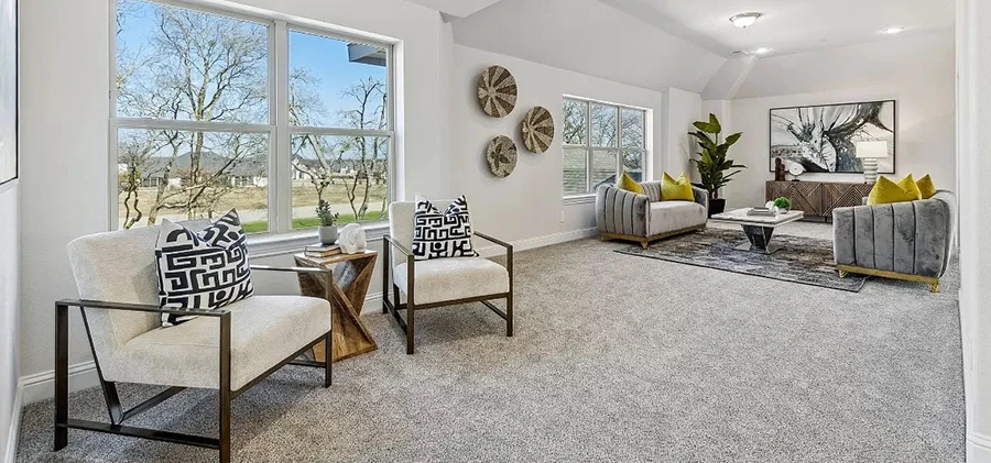 Spacious Prestonwood game room or loft area professionally staged with two gray velvet sofas, white accent chairs, and neutral wall decor