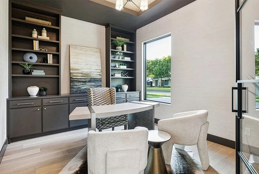 Sophisticated home office staging featuring gray built-in shelving, a modern curved desk, and two white guest chairs