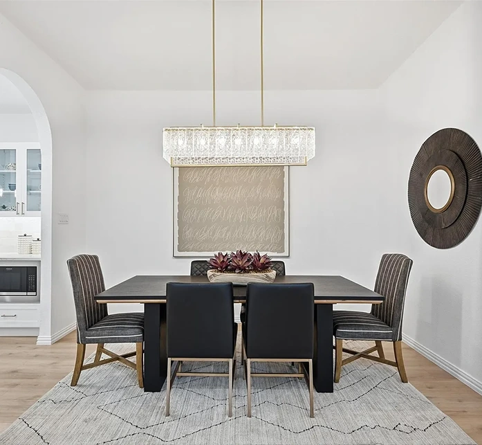 Staged dining room in Prestonwood featuring a dark wood table, black leather and striped upholstered chairs, and a glamorous rectangular crystal chandelier