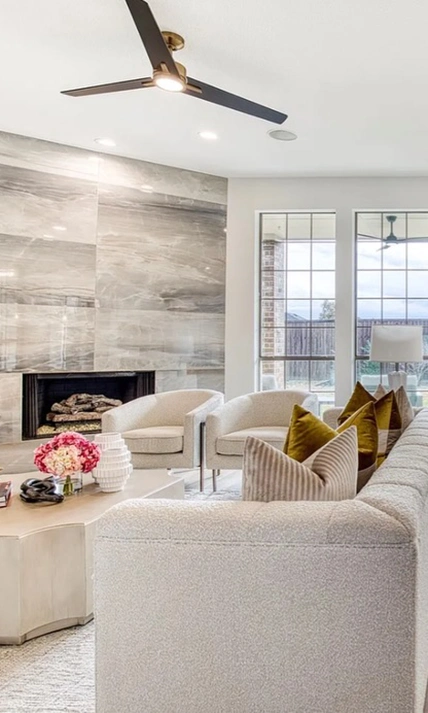 Close up of staged living room with two white accent chairs, round coffee table and gold and white pillors on the white sofa