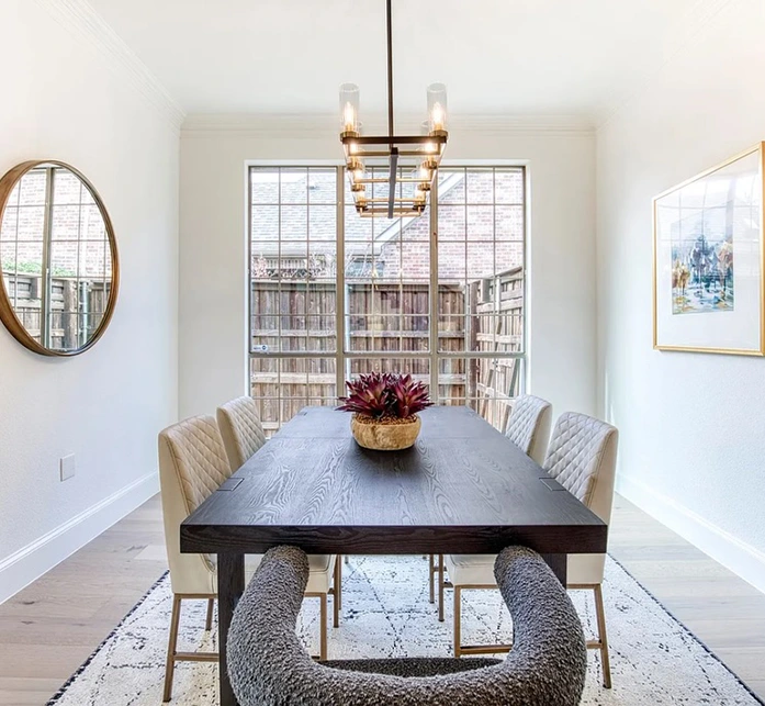 Staged dining room with large wooden rectangular table, four leather side chairs and two bouchle arm chairs