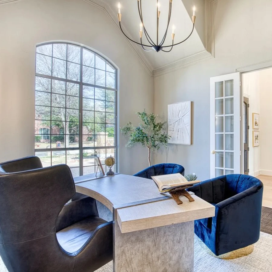 Staged office with grey modern desk, black leather desk chair and two velvet blue guest chairs