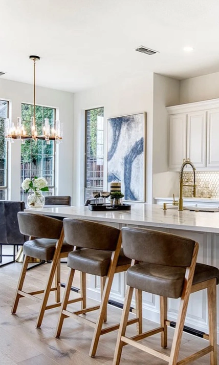 Modern kitchen staged with tan leather barstools, round table and chairs with kitchen accents
