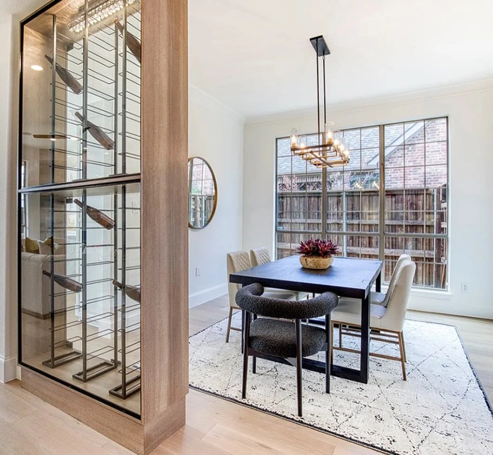 Staged dining room with modern table and chairs, round mirror and a wine wall