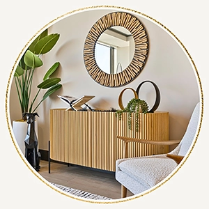 
            Circular inset image showing a fluted wood sideboard topped with modern decor, a black dog sculpture, and a large sunburst wall mirror