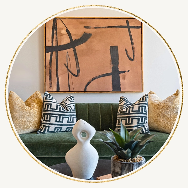 Circular inset image of a green velvet sofa with patterned throw pillows, positioned beneath a large earth-toned abstract painting