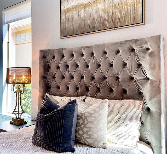 Close up of staged bedding with velvet headbaord and plush pillows