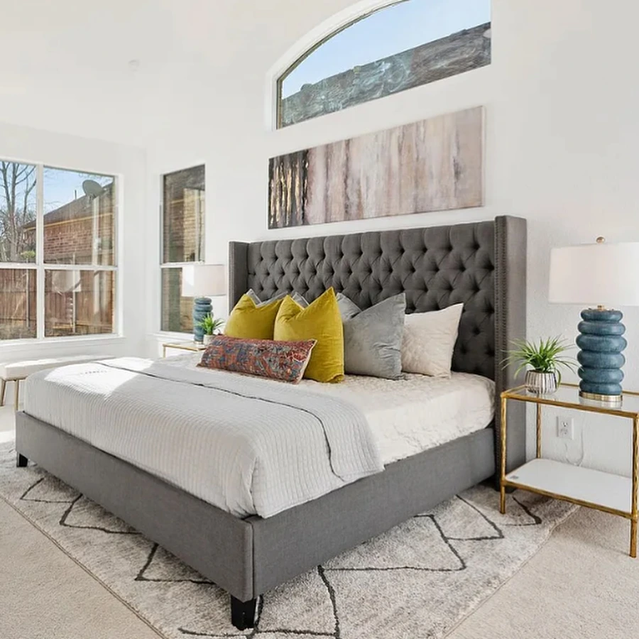 Staged bedroom with large upholstered grey bed, velvet pillows and large artwork