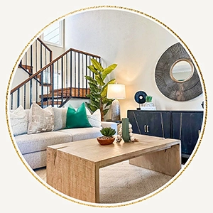 Staged living room with grey sofa, light wood coffee table, black console table and round mirror