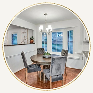 Staged dining room with round table and four velvet high back chairs