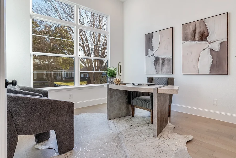Staged home office with modern desk, two guest chairs and rawhide rug