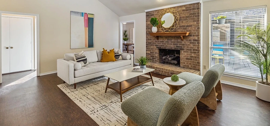 Staged living room with white sofa, two green plush chairs and coffee table